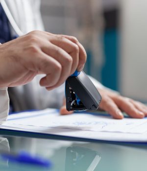 Médico carimbando documentos com o CRM médico em uma prancheta, representando a validação oficial do exercício profissional na medicina.