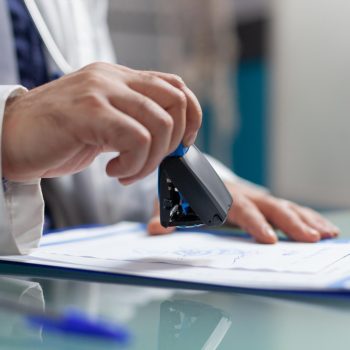 Médico carimbando documentos com o CRM médico em uma prancheta, representando a validação oficial do exercício profissional na medicina.
