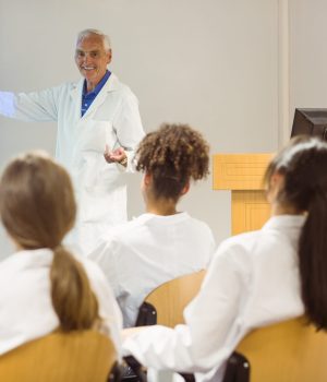 Professor de medicina explicando conteúdo em sala de aula para alunos com jaleco