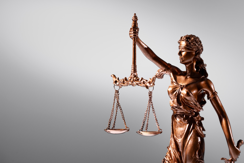Estátua de bronze da deusa da justiça com balança na mão, representando imparcialidade e equidade.
