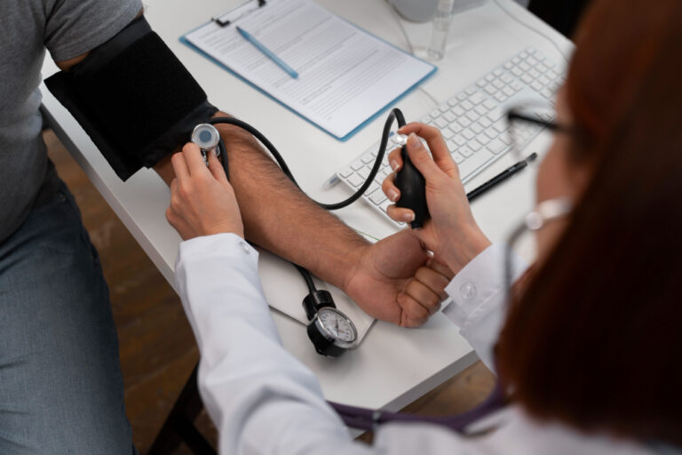 Profissional de saúde realiza a medição da pressão arterial de um paciente utilizando um esfigmomanômetro em consultório médico.
