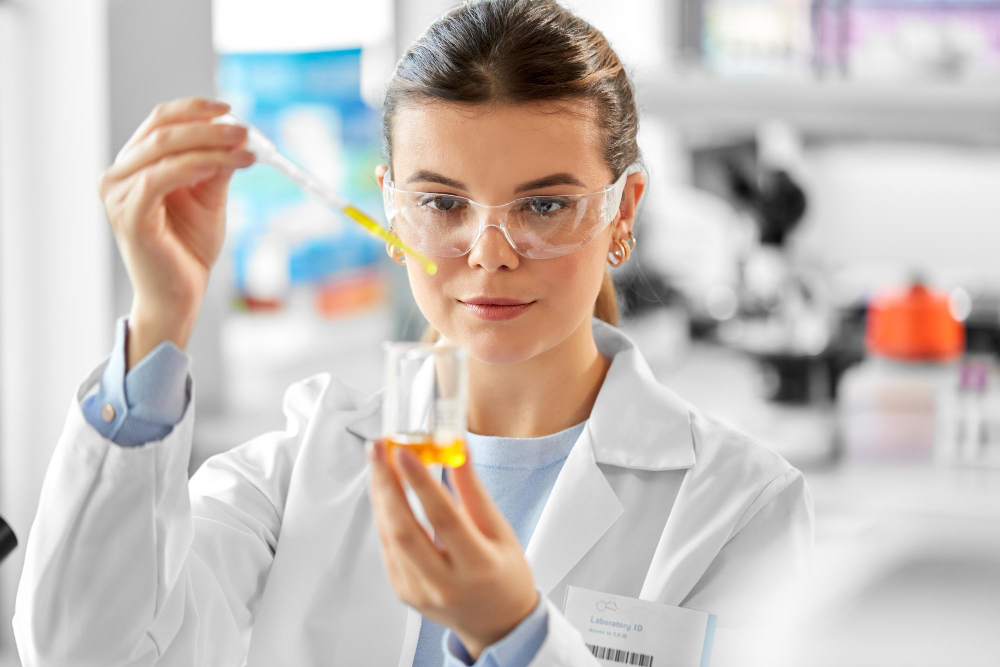 Cientista manipulando líquido amarelo com pipeta em laboratório.