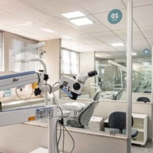 Consultório odontológico moderno, com divisórias de vidro e equipamento de microscopia.