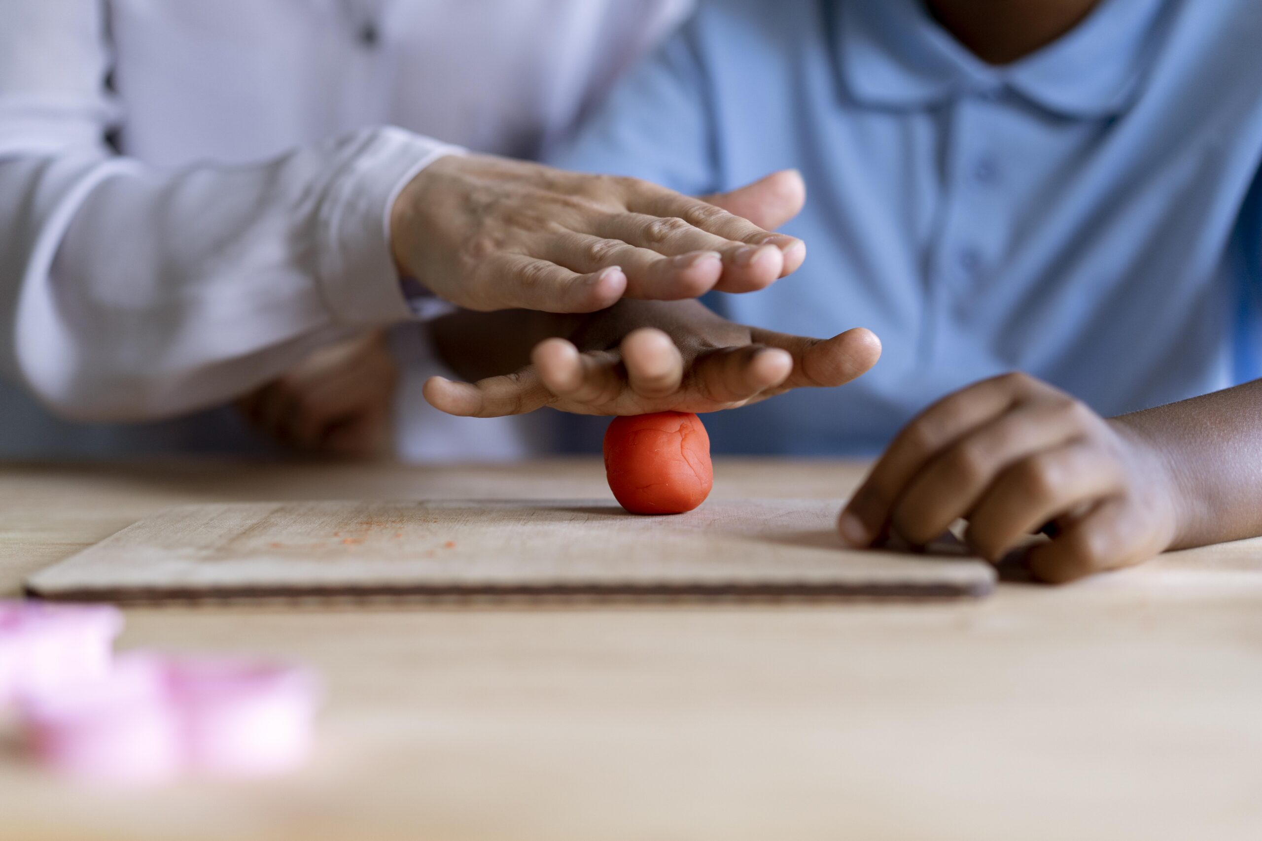 Profissional conduz atividade com massinha durante sessão de terapia ocupacional infantil.