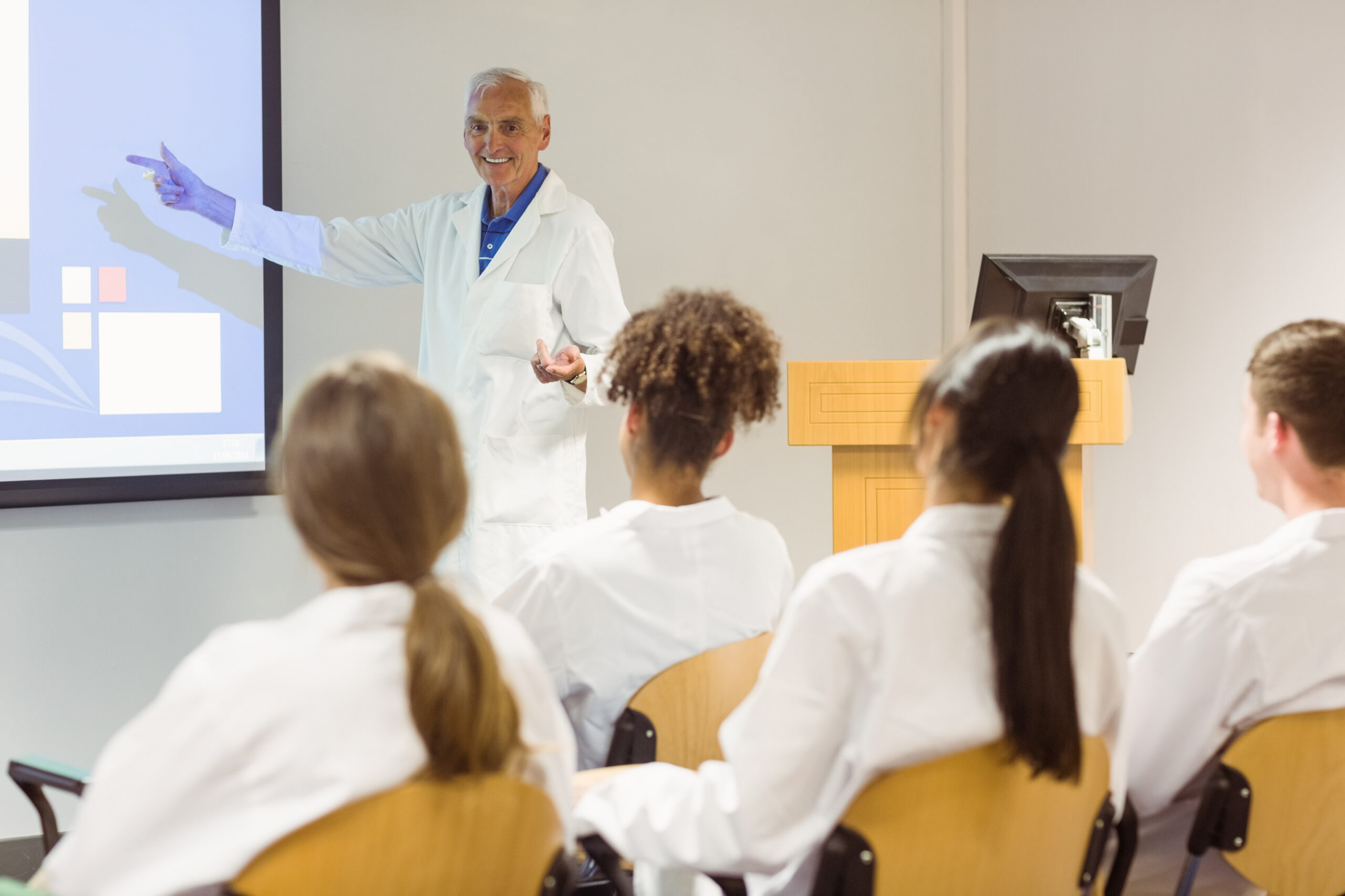 Professor de medicina explicando conteúdo em sala de aula para alunos com jaleco